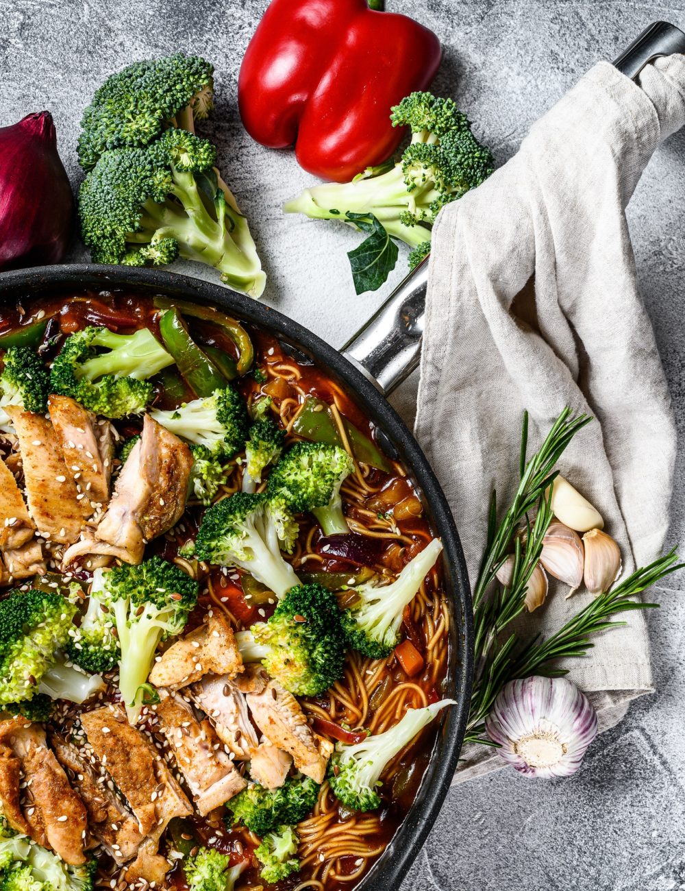 Udon stir-fry noodles with chicken in a pan. Gray background. Top view